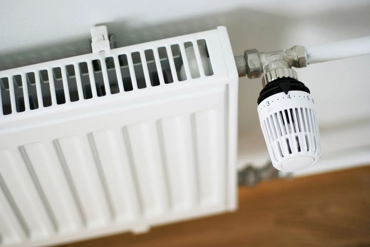 A white heater sitting on top of a wooden floor.